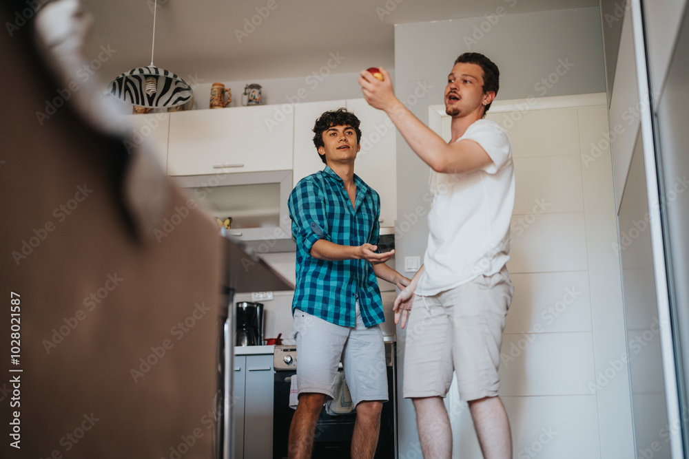 Two young men having fun in a modern kitchen, casually interacting in a relaxed and playful manner. The scene captures a sense of friendship and leisure in a contemporary home environment. Two young men having fun in a modern kitchen, casually interacting in a relaxed and playful manner. The scene captures a sense of friendship and leisure in a contemporary home environment.
