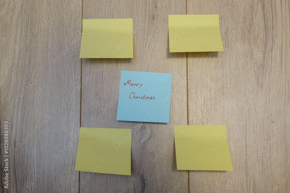 Merry Christmas written on sticky notes on a wooden background Merry Christmas written on sticky notes on a wooden background