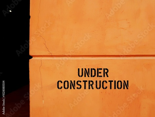 Orange copy space wall with text written UNDER CONSTRUCTION, refers to unfinished building, structure or project, but actively being worked on photo