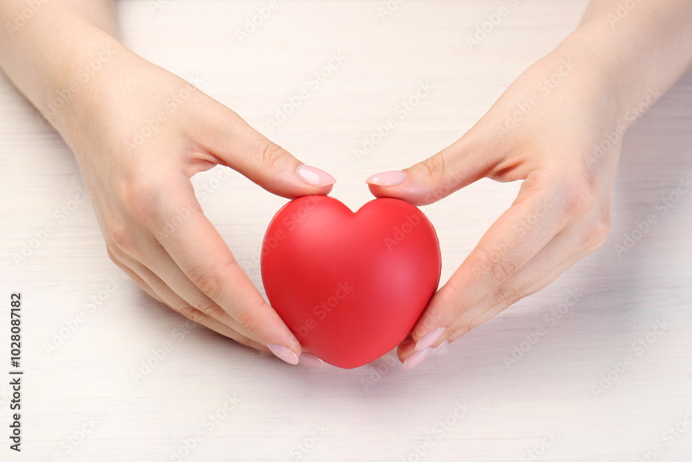 Woman with red decorative heart at white wooden table, closeup