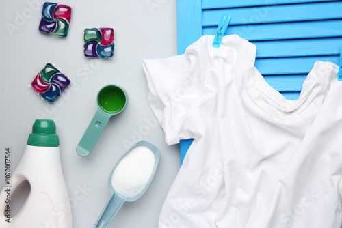 Different laundry detergents and t-shirt on grey background, flat lay