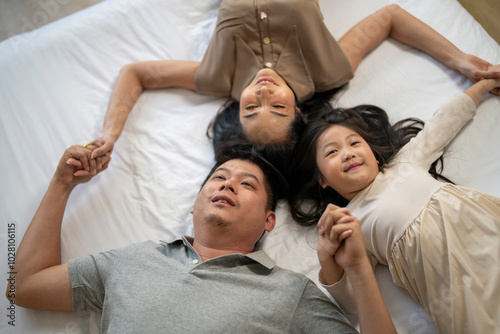 A joyful mother and daughter laughing together while lying on a bed. The playful moment showcases their strong bond and happiness in a comfortable home setting, surrounded by natural decor.