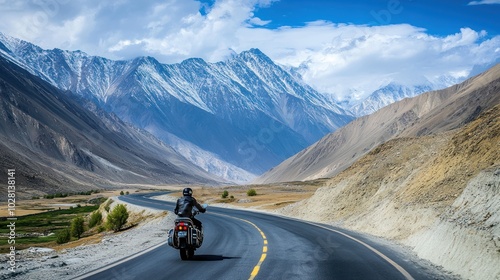 Motorcycle road trip through mountains, showcasing a curving mountain road with a motorcyclist riding through scenic, high-altitude landscapes, symbolizing freedom and adventure on two wheels.