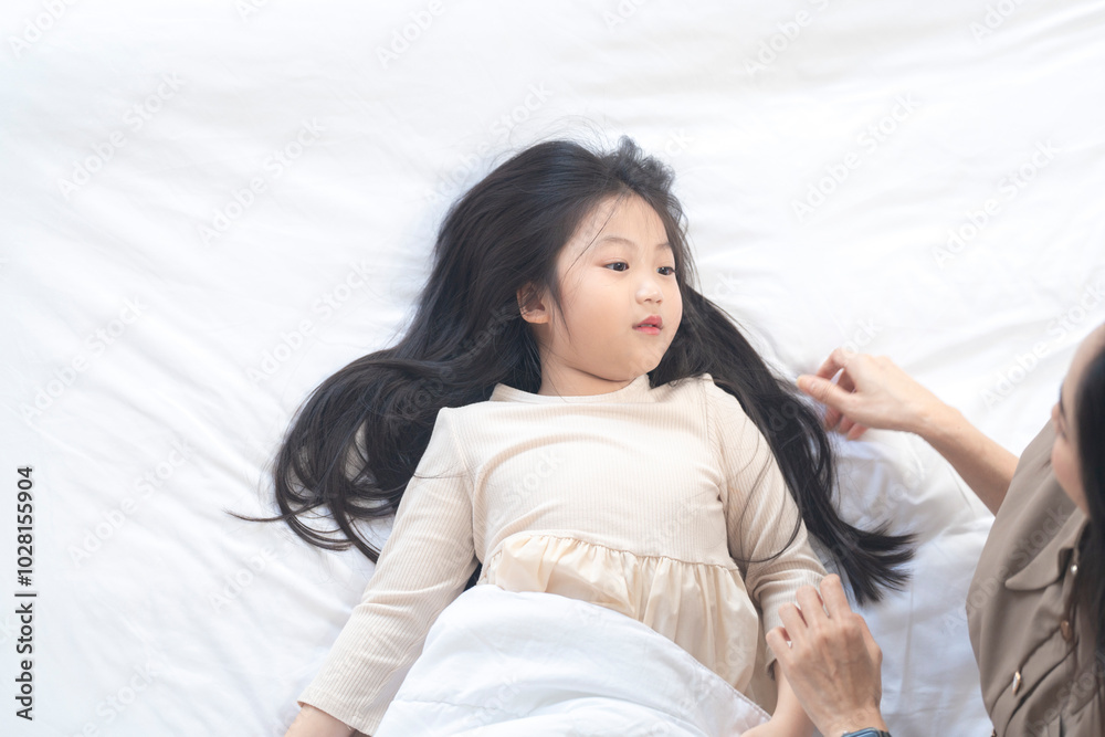 A joyful mother and daughter laughing together while lying on a bed. The playful moment showcases their strong bond and happiness in a comfortable home setting, surrounded by natural decor. A joyful mother and daughter laughing together while lying on a bed. The playful moment showcases their strong bond and happiness in a comfortable home setting, surrounded by natural decor.
