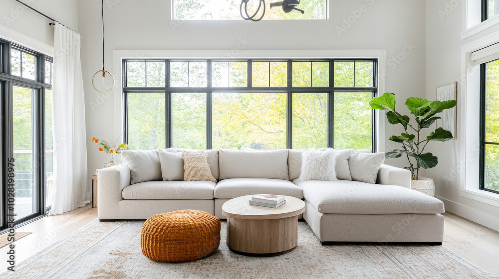 Fototapeta premium A modern living room featuring spacious white sectional sofa, round coffee table, and cozy pouf. Large windows allow natural light to fill space, enhancing serene atmosphere