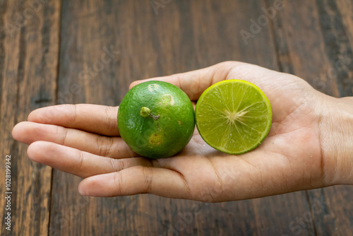 jeruk nipis or Lime green with cut in half and slices isolated on wooden background.