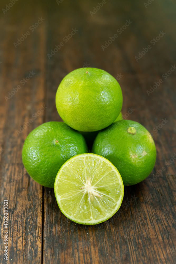 jeruk nipis or Lime green with cut in half and slices isolated on wooden background. jeruk nipis or Lime green with cut in half and slices isolated on wooden background.