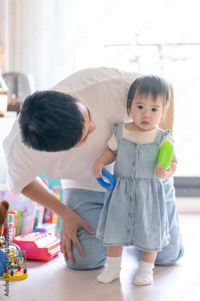 A 1 year old Taiwanese girl spending time playing happily with her parents, a man and woman in their 20s, in a room of a high rise apartment in Taichung City, Taiwan. A 1 year old Taiwanese girl spending time playing happily with her parents, a man and woman in their 20s, in a room of a high rise apartment in Taichung City, Taiwan.