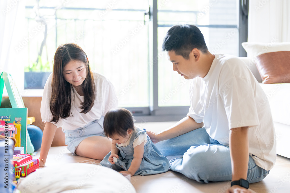 A 1 year old Taiwanese girl spending time playing happily with her parents, a man and woman in their 20s, in a room of a high rise apartment in Taichung City, Taiwan. A 1 year old Taiwanese girl spending time playing happily with her parents, a man and woman in their 20s, in a room of a high rise apartment in Taichung City, Taiwan.