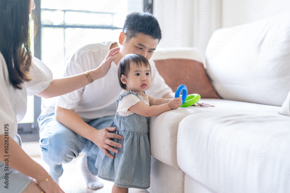 A 1 year old Taiwanese girl spending time playing happily with her parents, a man and woman in their 20s, in a room of a high rise apartment in Taichung City, Taiwan. A 1 year old Taiwanese girl spending time playing happily with her parents, a man and woman in their 20s, in a room of a high rise apartment in Taichung City, Taiwan.