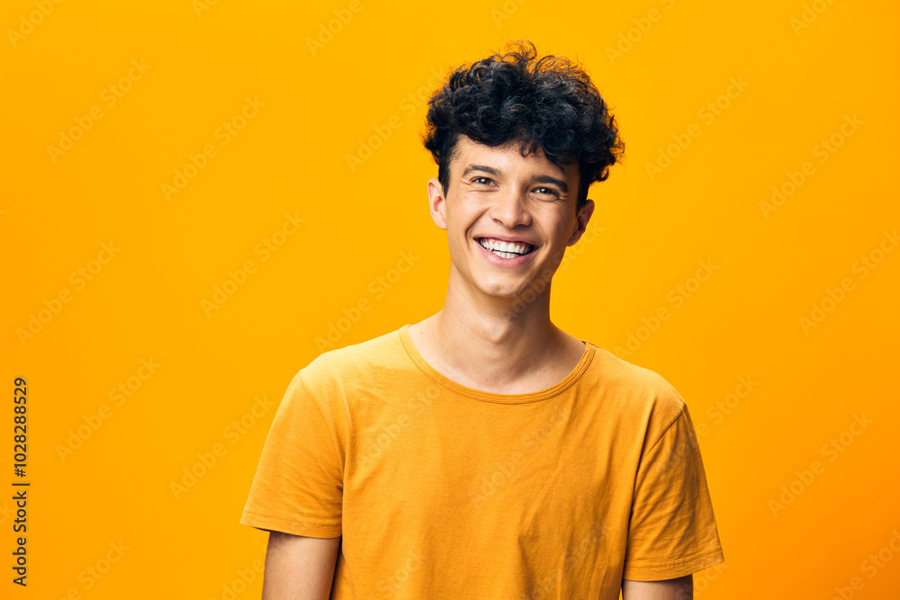 Smiling young man with curly hair on a bright yellow background, exuding happiness and positivity, ideal for concepts related to joy, youth, and self confidence Smiling young man with curly hair on a bright yellow background, exuding happiness and positivity, ideal for concepts related to joy, youth, and self confidence