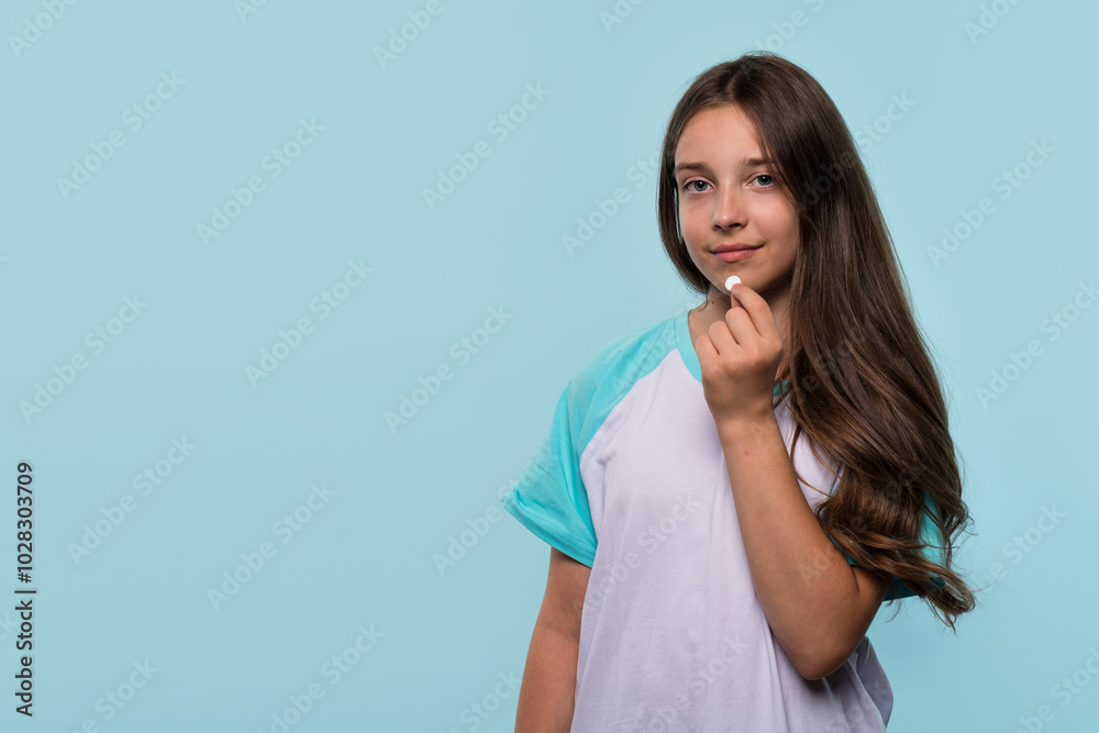 Young girl holds white pill near her mouth Young girl holds white pill near her mouth