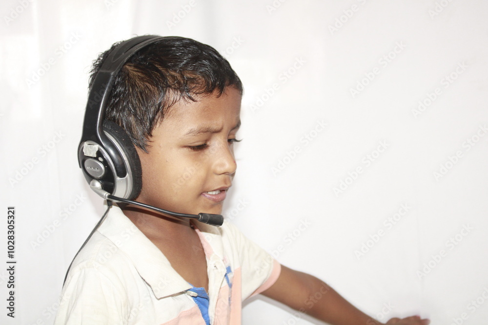 Portrait of cute littlie indian boy in headphones listening to music and smiling isolated over white background Portrait of cute littlie indian boy in headphones listening to music and smiling isolated over white background