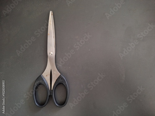 Used scissors in closed position on black dark gray background with copy space photo