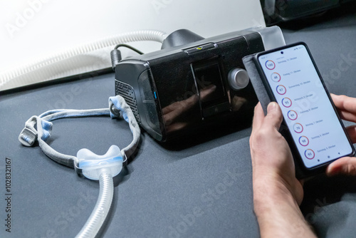Male European with cpap machine checking therapy analysis via smartphone app or medical app for e-health check and health report via mobile device for health analysis innovative sleep apnea mask apps