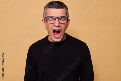 Caucasian guy feeling nervous and upset while shouting in frustration with his jaw clenched and voice raised showcasing aggression isolated over beige background