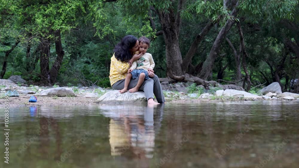 Isolated women spending quality time with son Sitting on Stone at Calm Lake Shore in the Morning Isolated women spending quality time with son Sitting on Stone at Calm Lake Shore in the Morning
