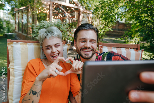 Happy man taking selfie with friend making heart shape with hands photo