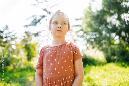 Girl standing in front of trees on sunny day photo