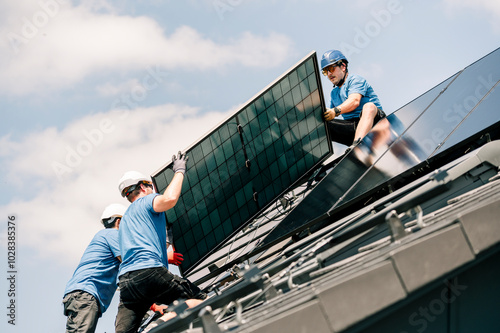 Engineers wearing hardhats and installing solar panels on rooftop photo