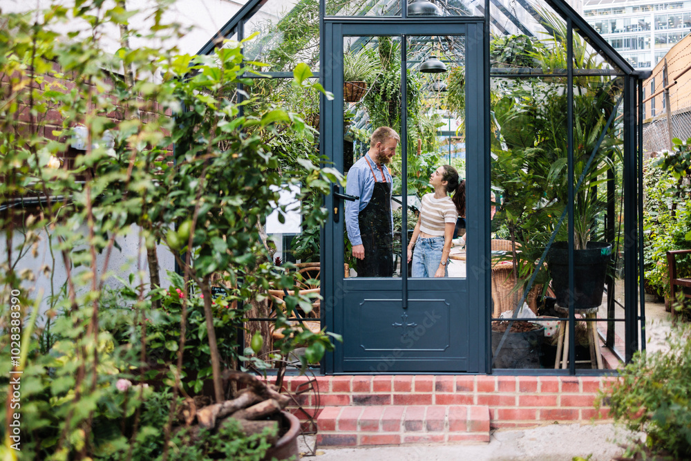 Couple standing and discussing in plant nursery Couple standing and discussing in plant nursery