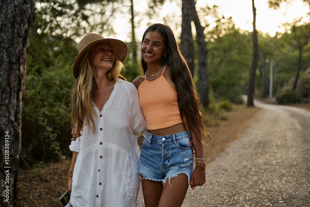 Happy mother and daughter with arm around walking on road Happy mother and daughter with arm around walking on road