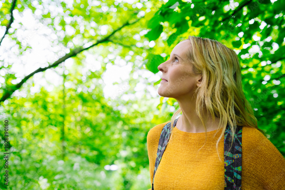 Mature woman looking up under tree in garden Mature woman looking up under tree in garden