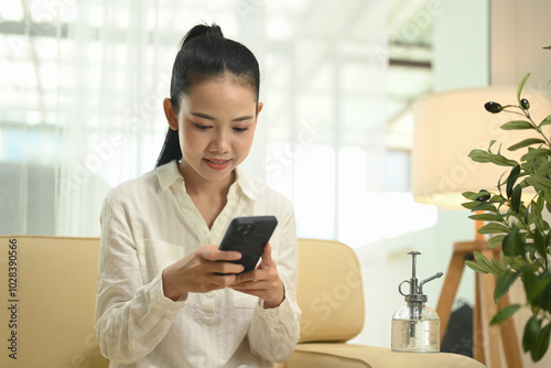 Beautiful young entrepreneur using mobile phone on sofa in her office