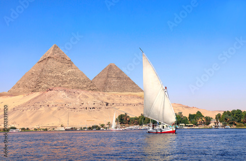 Tableau sur toile Famous Great Pyramids of Chephren and Cheops and traditional sailing boat felucca, Nile river, Egypt