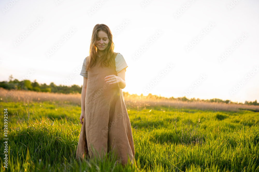 Smiling pregnant woman walking in green grass Smiling pregnant woman walking in green grass