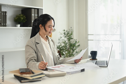 Professional businesswoman checking market research and using laptop at desk