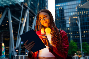 Smiling woman with headphones and long braided hair using tablet PC