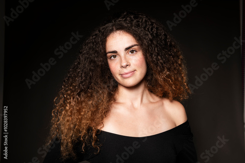 Smiling curly haired woman against black background photo