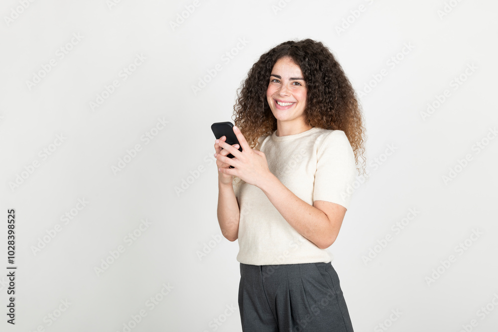 Happy young woman standing with smart phone against white background Happy young woman standing with smart phone against white background