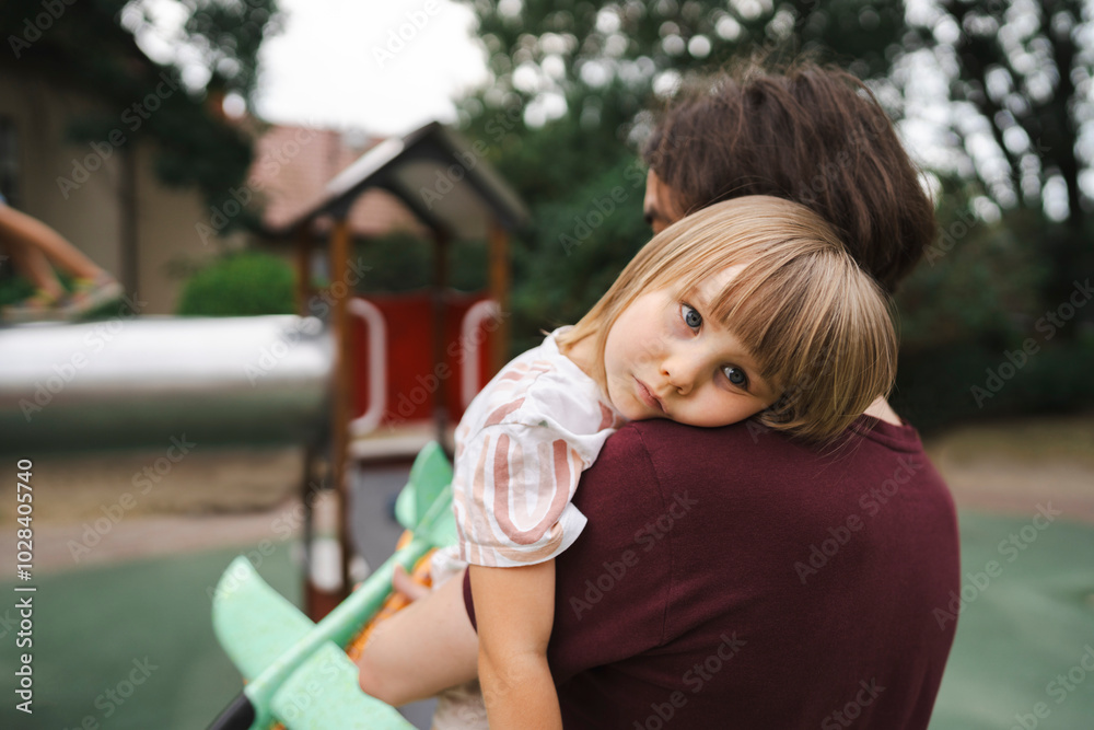 Tired girl resting on her father's shoulder at park Tired girl resting on her father's shoulder at park