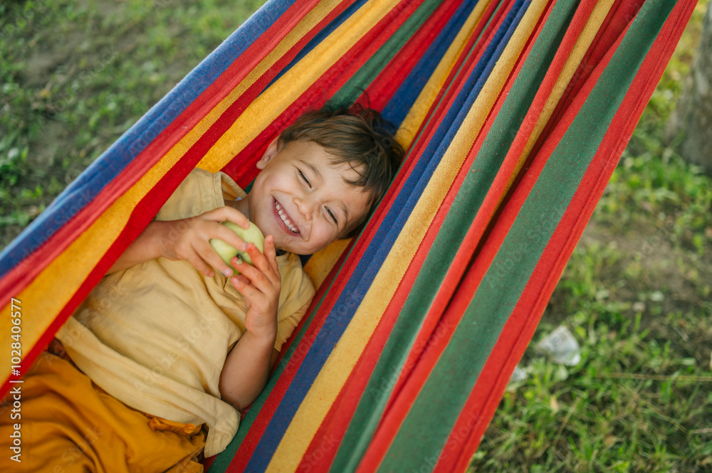Smiling boy with eyes closed lying in colorful hammock Smiling boy with eyes closed lying in colorful hammock