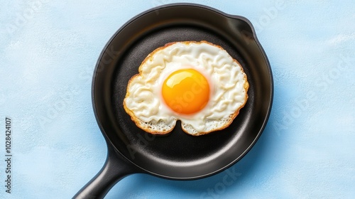 Fried egg on a black skillet against a light blue background photo