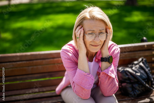 Portrait of mature woman in park. She is worried and depressed.