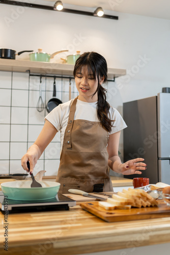 Asian woman grilling sausages and bacon for breakfast