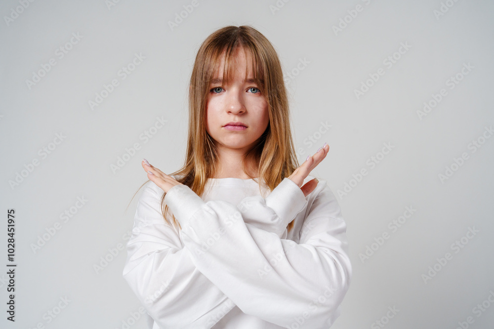 Young woman with long hair confidently poses with crossed arms against a plain background Young woman with long hair confidently poses with crossed arms against a plain background