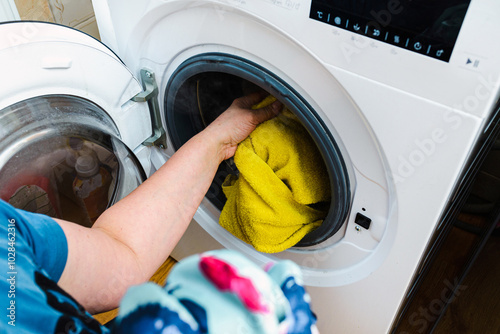Caucasian housewife takes clothes out of washing machine. closeup.
