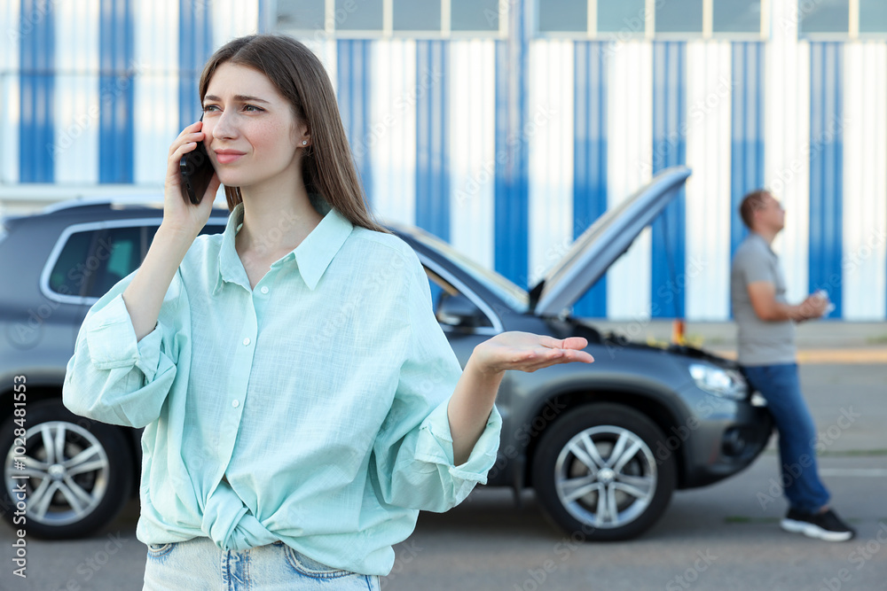 Man standing near broken auto while woman calling to car service outdoors Man standing near broken auto while woman calling to car service outdoors