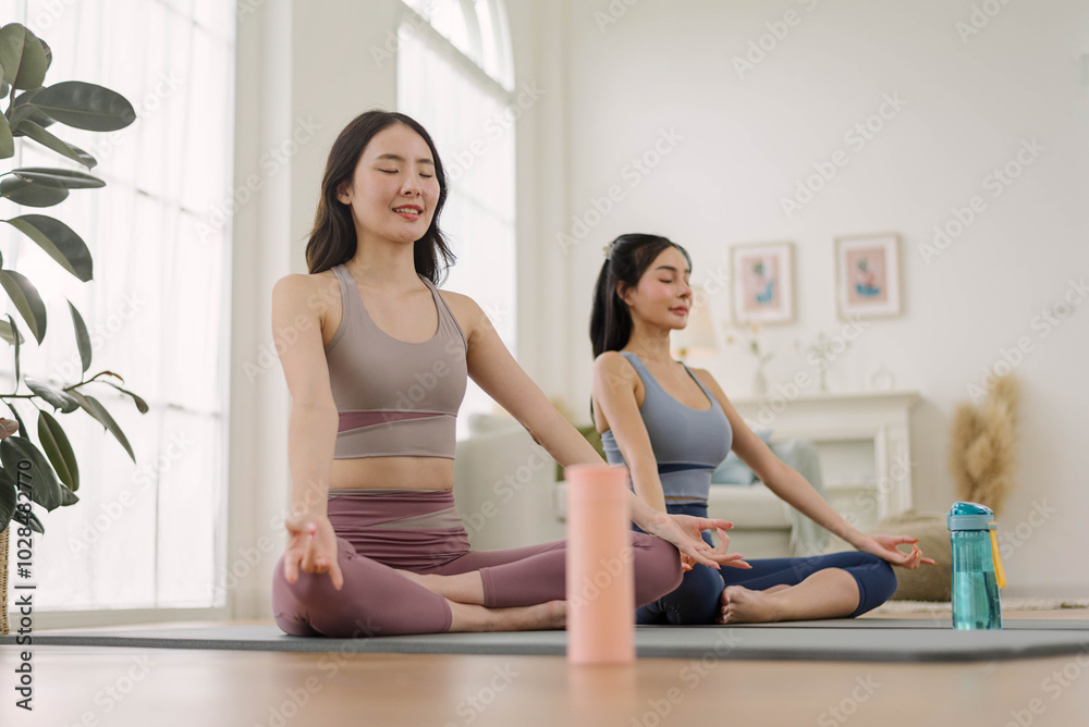 Two Asian woman wearing sportwear practicing yoga at home studio. Health care and wellness activities. Two Asian woman wearing sportwear practicing yoga at home studio. Health care and wellness activities.