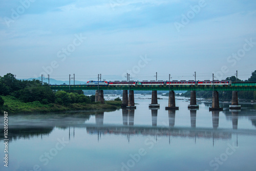 Jodong-ri, Chungju-si, Chungcheongbuk-do, Korea - September 6, 2019:  Train is crossing a bridge on Namhan River with morning fog. photo