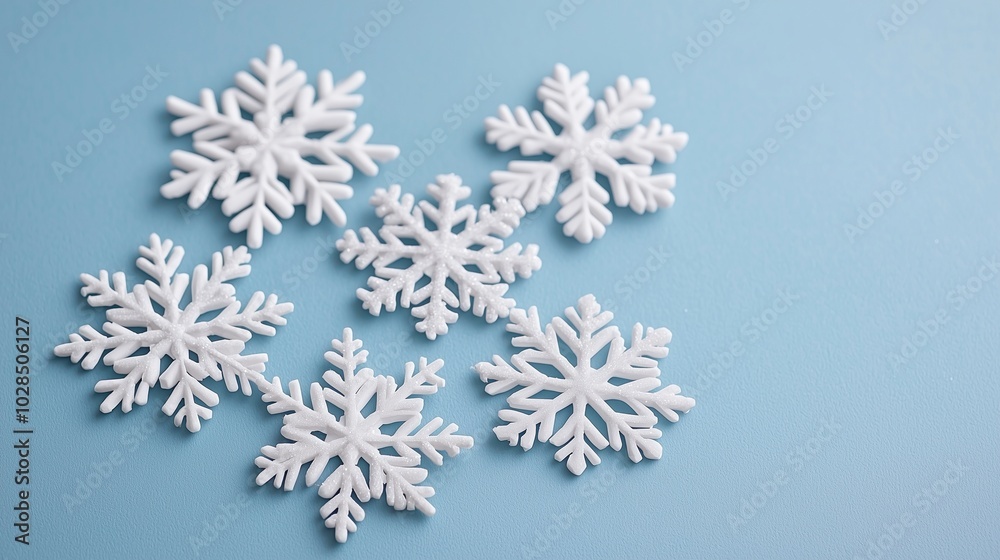 Delicate white snowflakes arranged on a soft blue surface, creating a serene winter atmosphere. Delicate white snowflakes arranged on a soft blue surface, creating a serene winter atmosphere.
