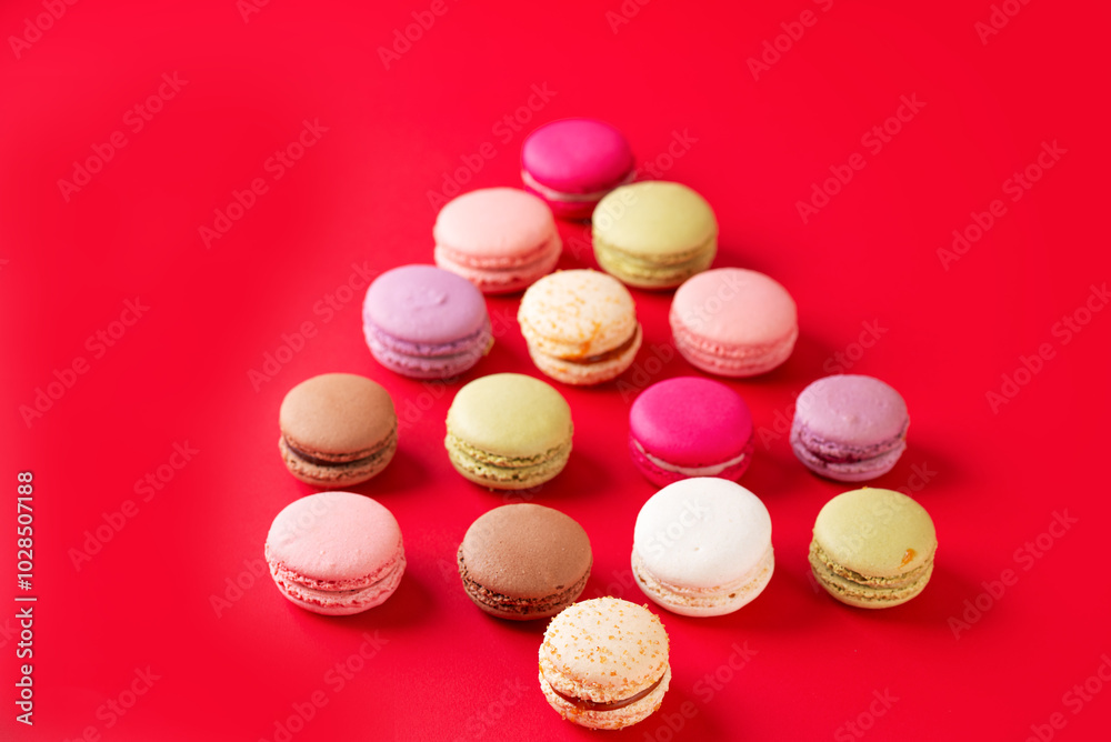 Obraz premium Multicolored macarons in the form of a Christmas tree on a red background.
