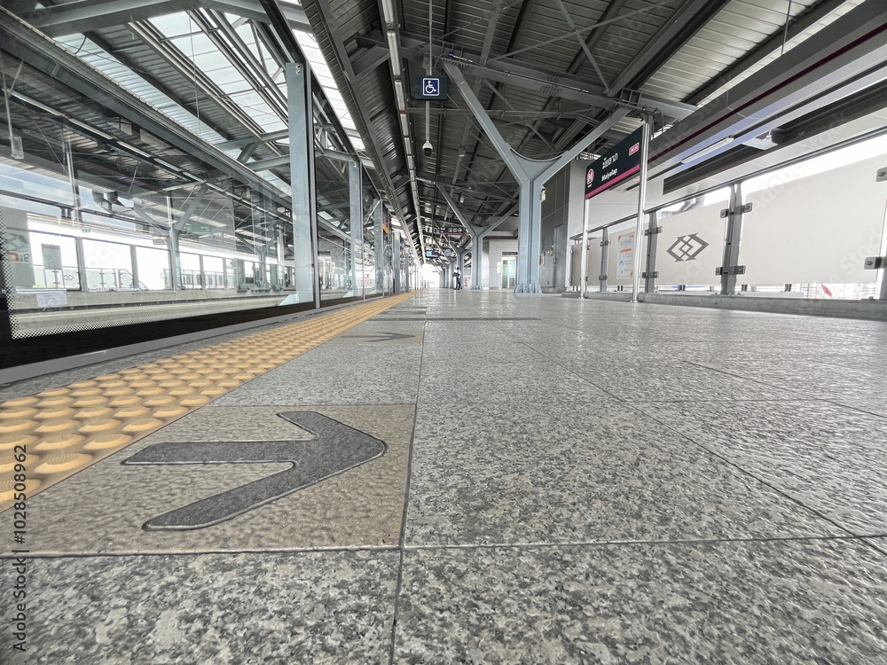 Modern Urban Train Station Platform with Steel Architecture and Directional Arrows for Commuters in a Contemporary City Environment