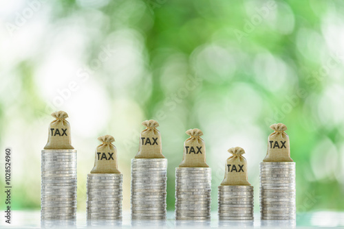 Tax collection, tax credit and benefit, financial concept : Tax bags rest atop coin stacks, depicting mandatory financial charge, type of levy imposed by a government on a taxpayer, individuals, etc.