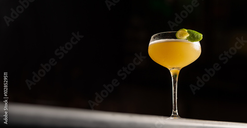 фотографія A glass of margarita cocktail with lime peel on a black background, bunner size, copy space