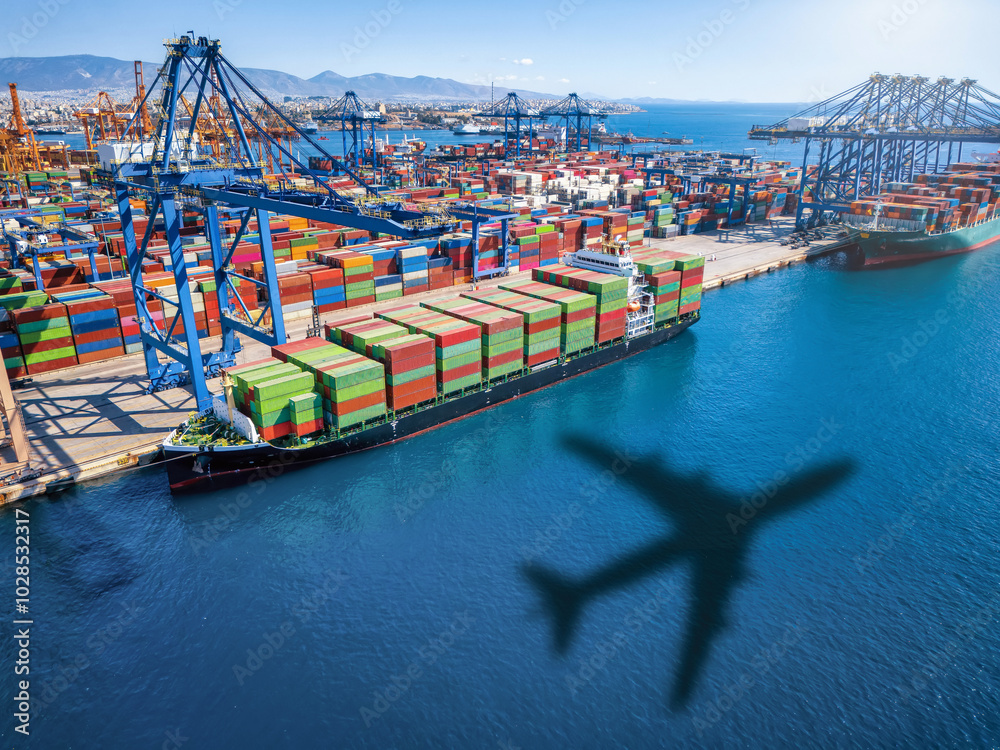Conceptual aerial top view of a cargo plane shadow flying above container freight port with docked ships and loading by cranes and trucks